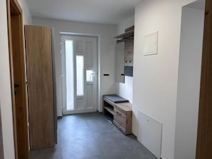 A hallway with a wooden door, a bench, and a wall-mounted shelf. - Apartment Angelina (Cerklje na Gorenjskem)