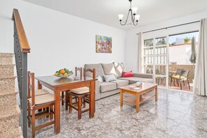 A living room with a sofa, a dining table, chairs, a chandelier, and a painting on the wall. - AP429 CASA ANGELINES (Nerja)