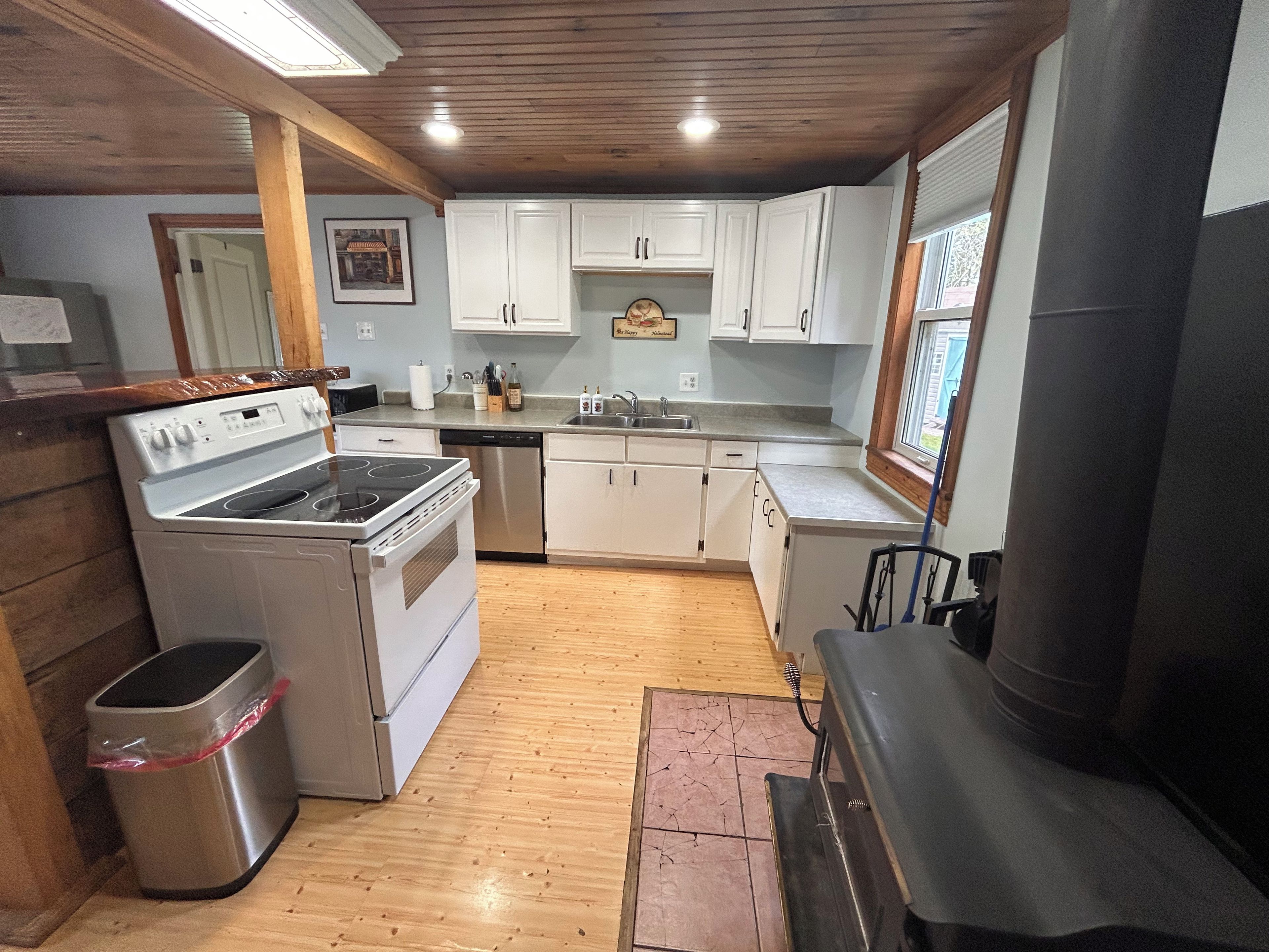 A compact kitchen with white cabinets, a stainless steel stove, and a dishwasher.