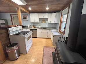 A compact kitchen with white cabinets, a stainless steel stove, and a dishwasher.