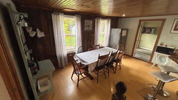A dining area with a wooden table and chairs, a refrigerator, and a microwave.