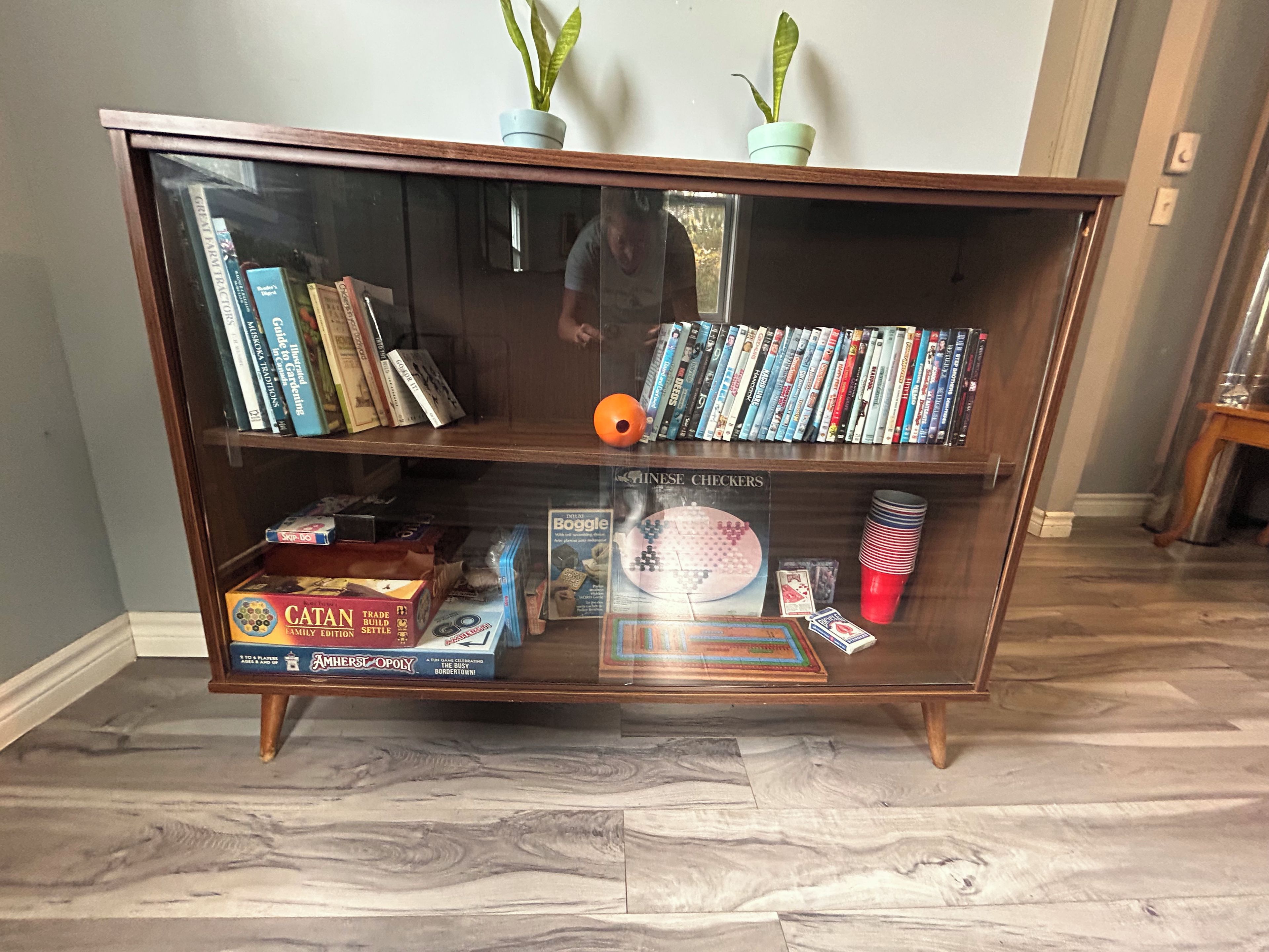 A wooden bookshelf with books, DVDs, and board games.