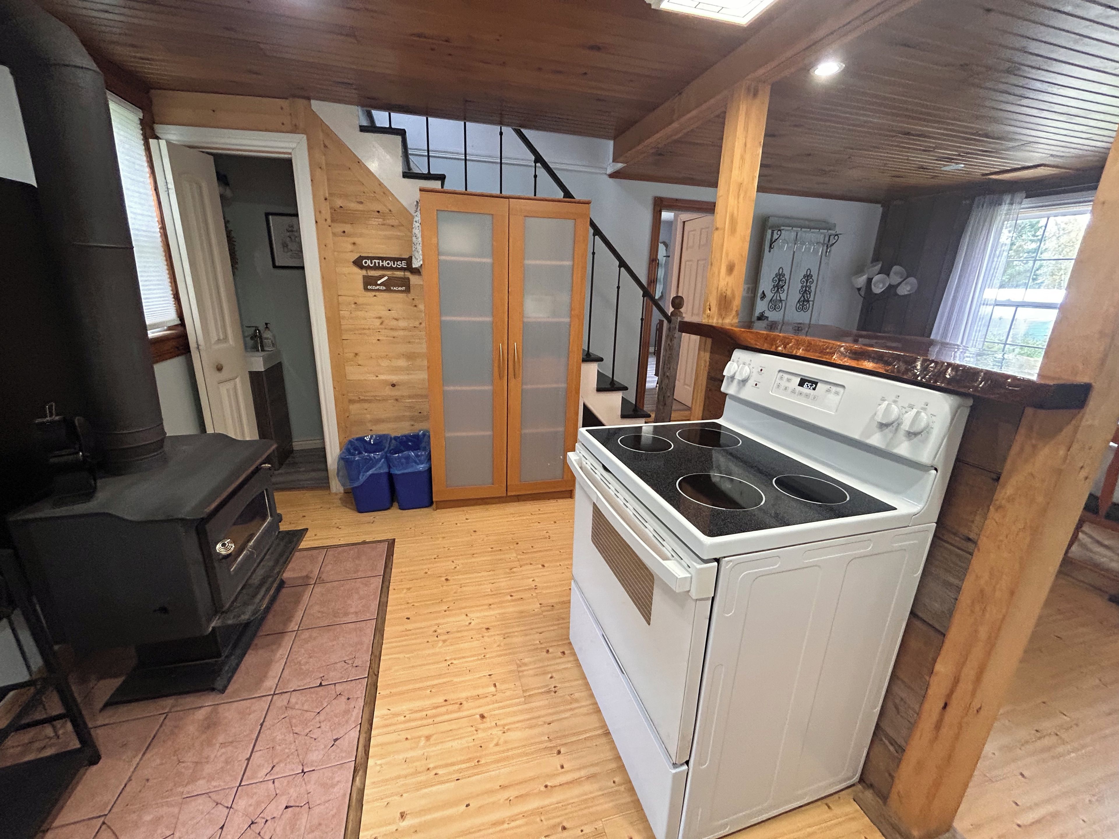A kitchen with a stove, a wood stove, and a staircase leading to an upper level.