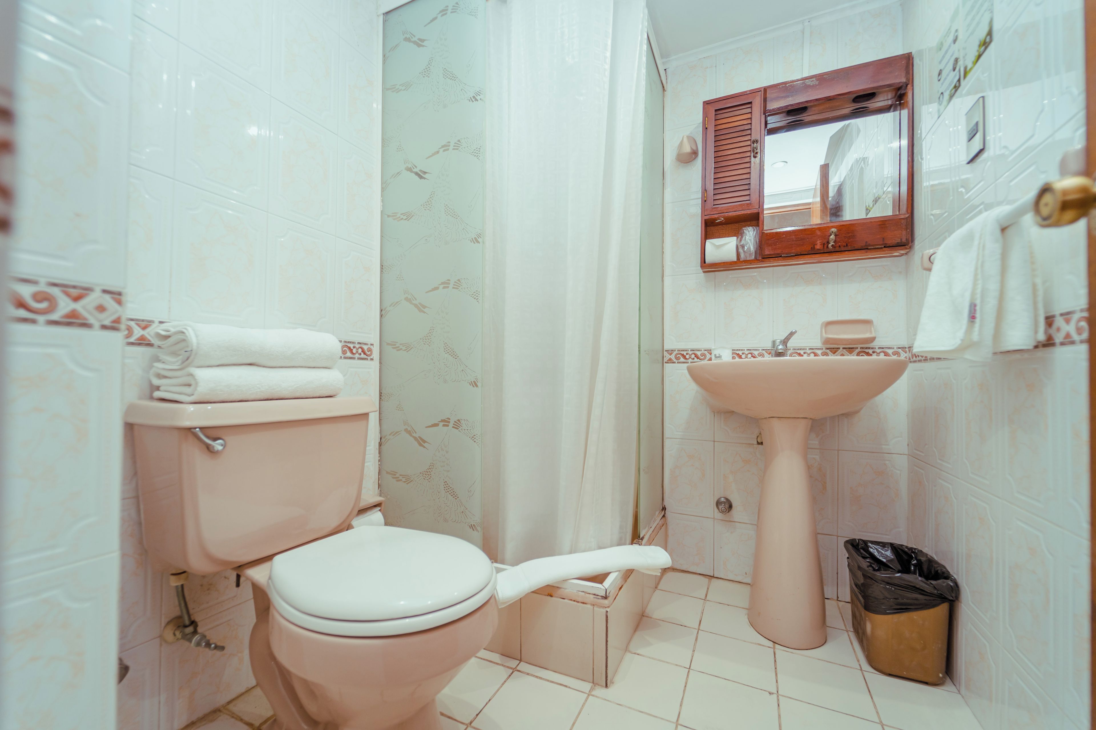 Un baño con inodoro, lavamanos y cortina de ducha.