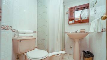 Un baño con inodoro, lavamanos y cortina de ducha.