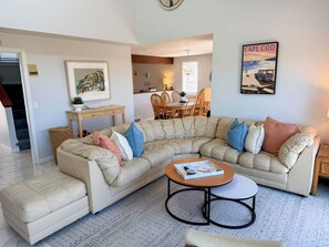A living room with a sectional sofa, a coffee table, and a dining area with chairs and a table. - New to our 2027 Inventory! Amazing views of Bass River Marina (West Dennis)