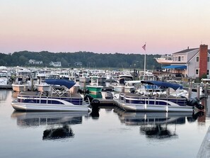 A marina with multiple boats docked, a flag, and a building with a blue awning. - New to our 2027 Inventory! Amazing views of Bass River Marina (West Dennis)