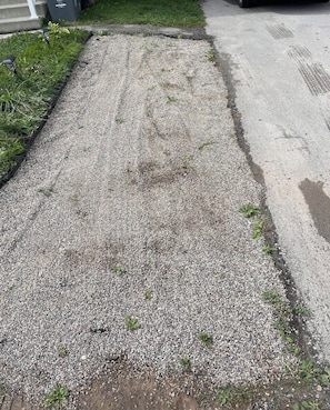 A gravel driveway with a concrete border and a grassy area with plants. - Canal Private Suite - Welland (Welland)