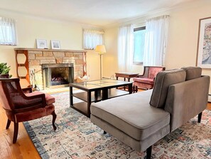 A living room with a fireplace, a sofa, a coffee table, and a patterned rug. - Comfort & convenience near Cleveland attractions! (Parma)
