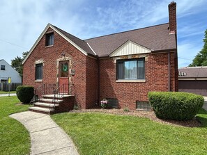 A two-story brick house with a front entrance, a small porch, and a visible garage door. - Comfort & convenience near Cleveland attractions! (Parma)
