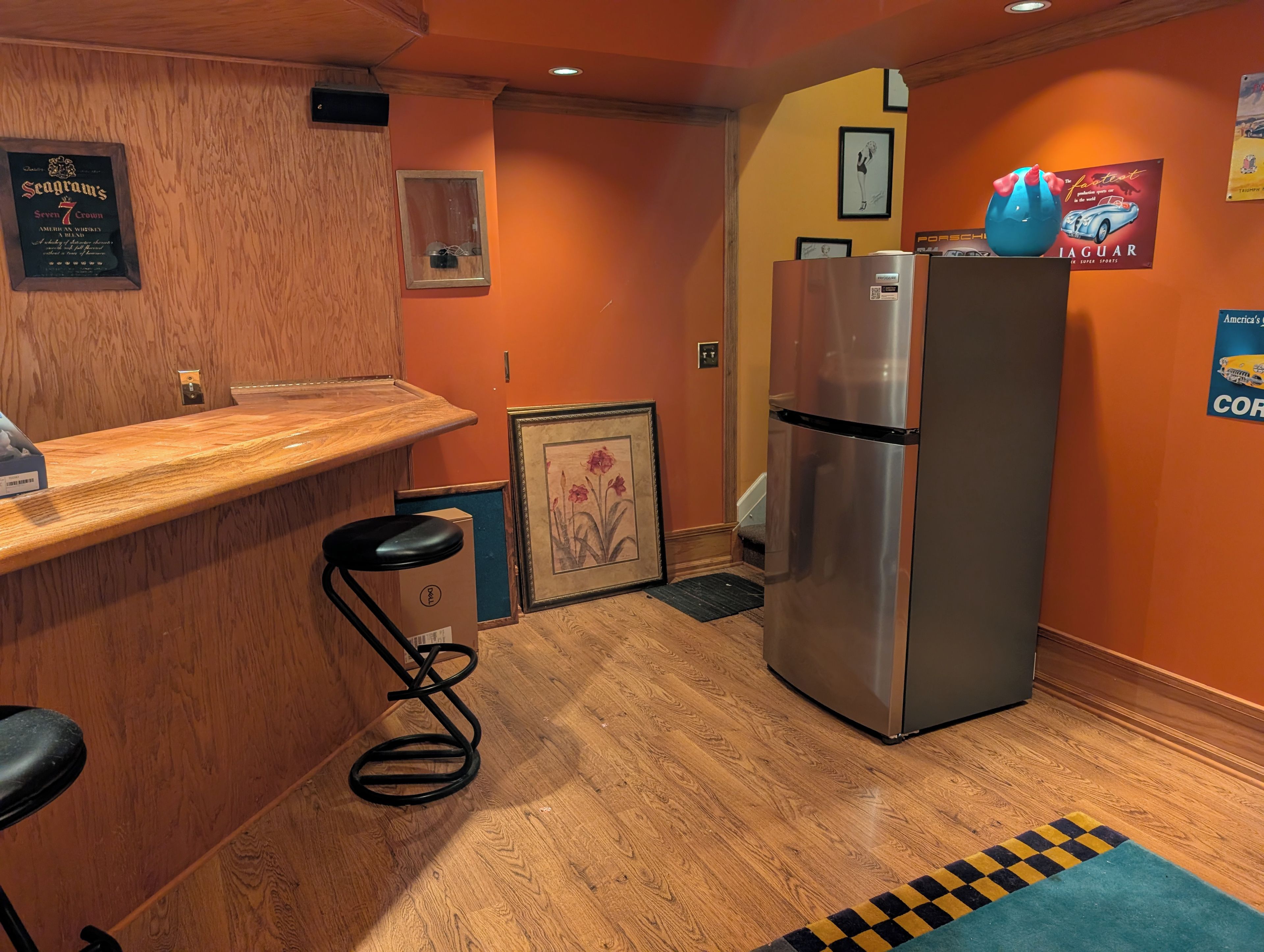A compact kitchen with a wooden countertop, a stainless steel refrigerator, and a framed picture on the wall.