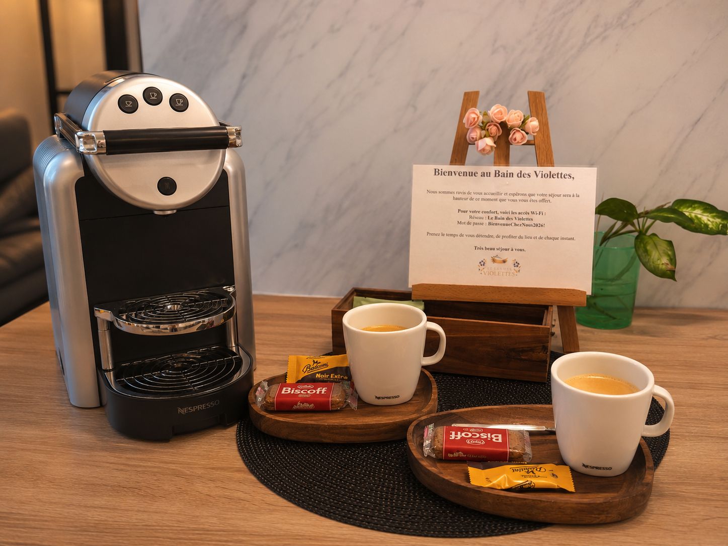 A coffee machine, two cups of coffee, a menu sign, and some snacks on a table.