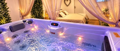 A spa room with a hot tub, a bed, and a heart-shaped wall decoration.