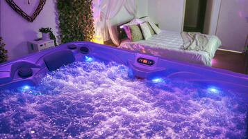 Een kamer met een bed, een wandplant en een bubbelbad.