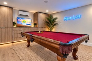 Een pooltafel met een rode viltbekleding, omringd door houten kasten en een neonreclame.