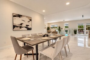 A modern dining area with a long table set for six, surrounded by chairs. - Private Oasis 5 Bed 4 Bth w Heated Pool Great for Families and Large Groups (Miami)