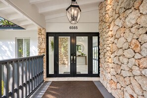 A hotel entrance with a stone wall, a black door with glass panels, and a number '6565' above. - Private Oasis 5 Bed 4 Bth w Heated Pool Great for Families and Large Groups (Miami)
