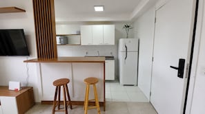 Eine kleine Küche mit einer Holztresen, zwei Barhocker, einem Kühlschrank und einer Mikrowelle.