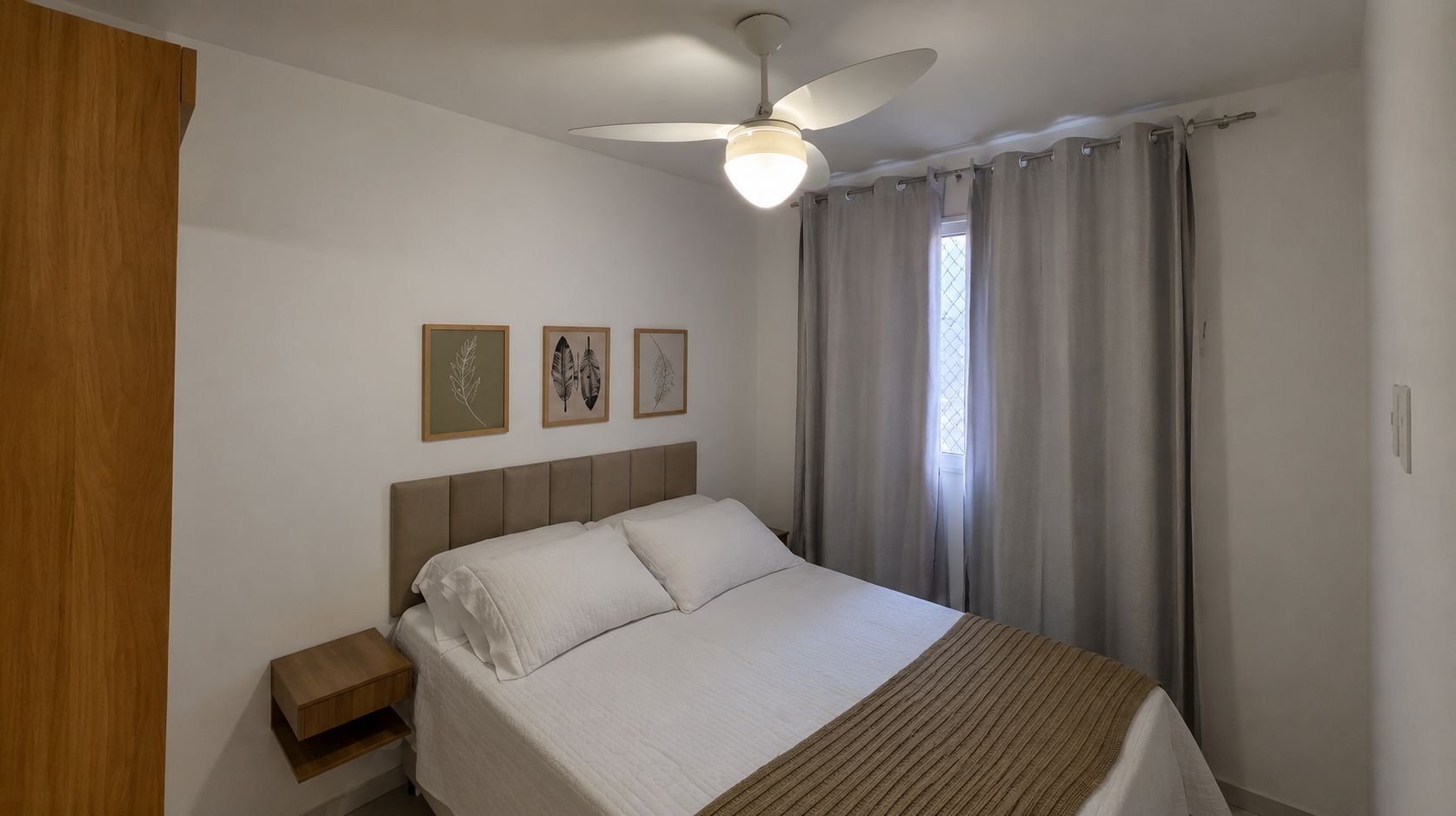 A bedroom with a bed, a nightstand, a ceiling fan, and a window with curtains.