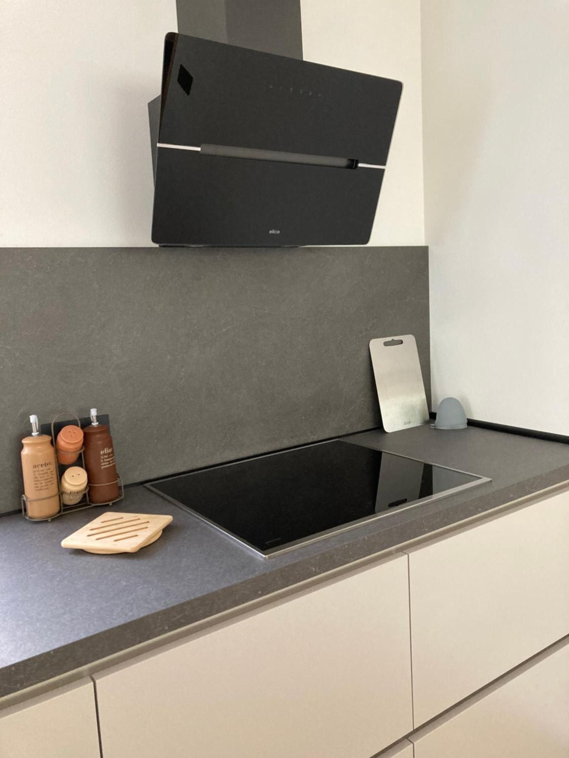 A modern kitchen with a black induction cooktop, a built-in oven, and a coffee machine.