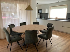 A modern kitchen with white cabinets, a round wooden table, and six grey chairs. - Apartment 'Pe De Munt Mez Col' with Mountain View, Balcony and Wi-Fi (La Valle)