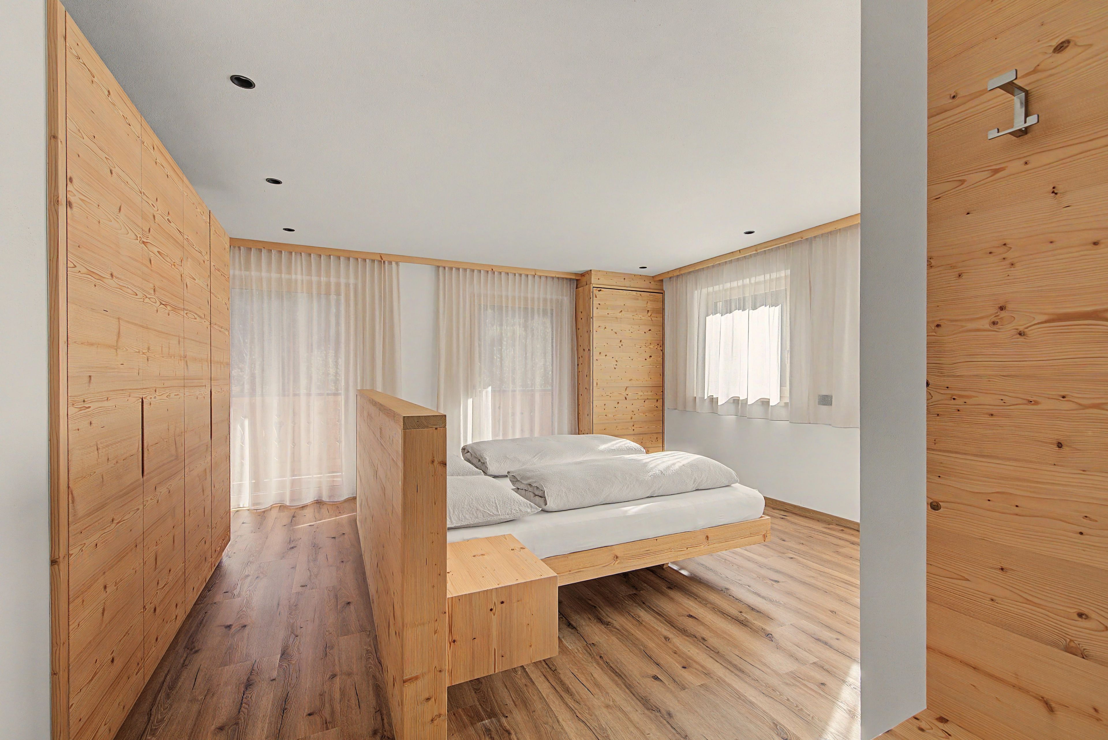 Une chambre à coucher avec un lit en bois, une armoire en bois et un plancher en bois.