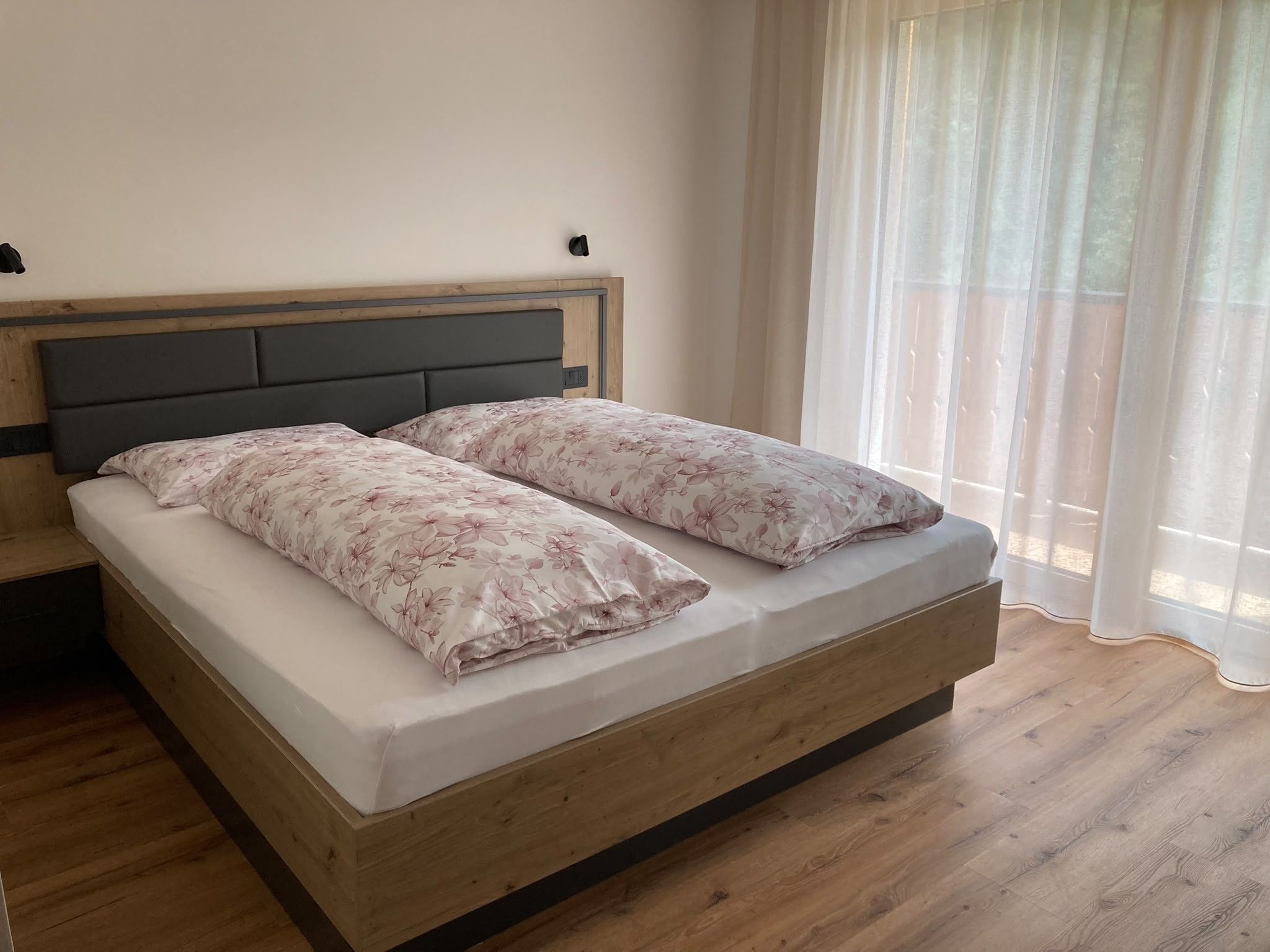 Een enkel bed met houten frame en hoofdbord, plus een nachtkastje.