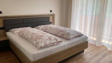 Een enkel bed met houten frame en hoofdbord, plus een nachtkastje.