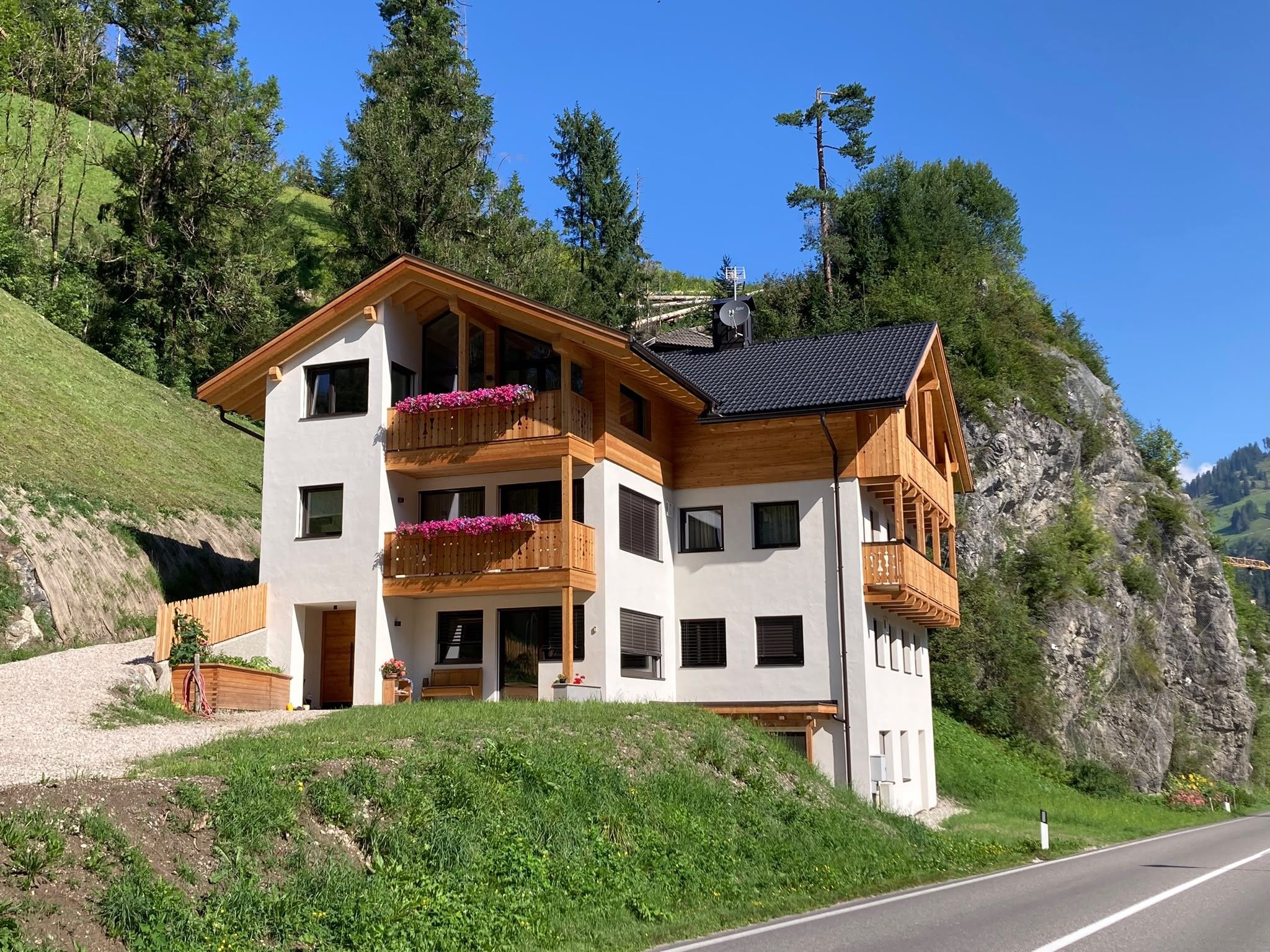 A two-story chalet with a balcony, situated on a hillside with a clear view of the surrounding landscape.