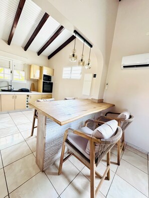 A kitchen with a wooden island, built-in cabinets, and a hanging light fixture. - Villa Between Land and Sea (Les Anses-d'Arlet)
