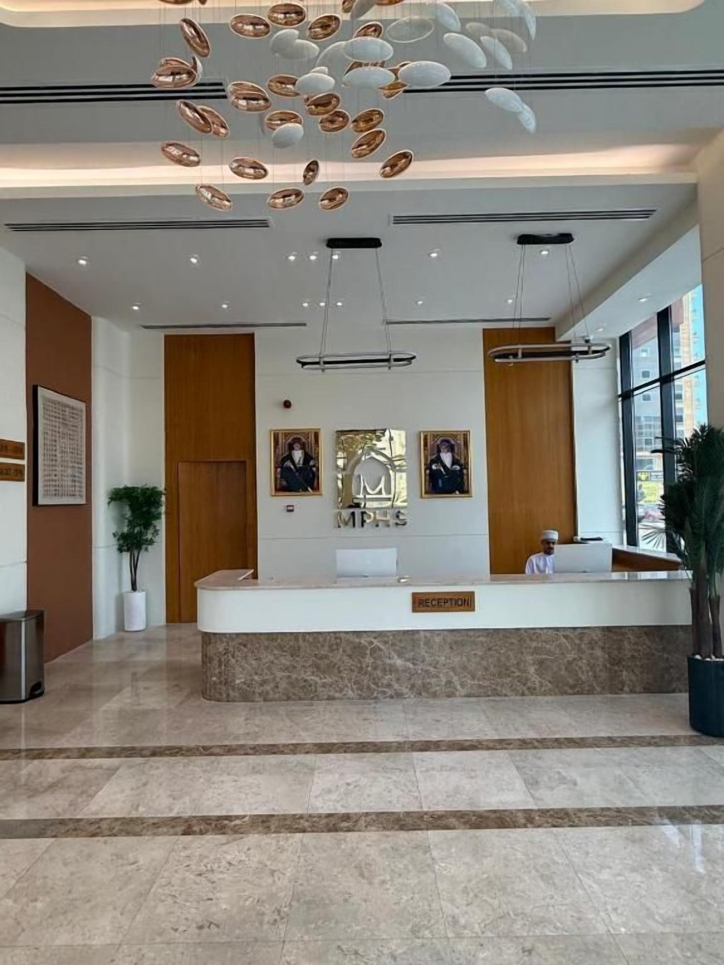 A reception desk with a marble counter, framed pictures above, and a modern chandelier.