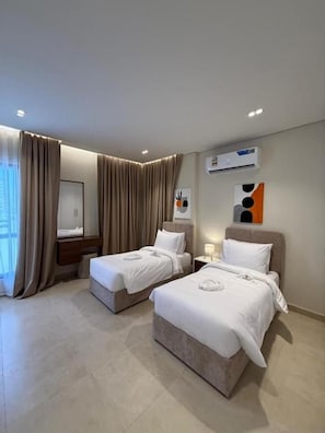 A hotel room with two beds, a large window with curtains, an air conditioning unit, and a wall-mounted artwork. - Al Montazah Park Hotel Suites (Salalah)