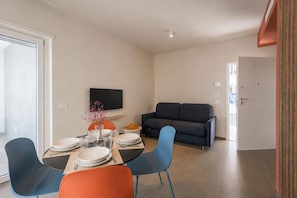 A modern living space with a dining area, a sofa, and a television. - Oltrevista Terrace By the Sea (Monopoli)