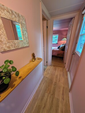 A hallway with a wooden bench, a potted plant, and a mirror on the wall.