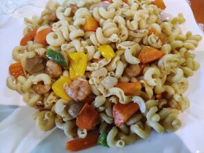 Un plato de pasta con verduras y carne.