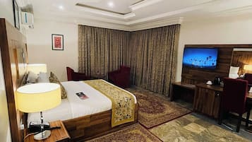 A hotel room with a bed, a desk, a TV, and a bathroom.
