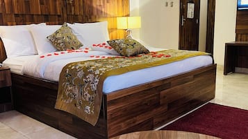 A hotel room with a wooden bed, a round table, and a TV on the wall.