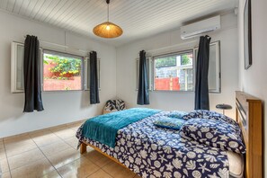 A bedroom with a bed, two windows, a hanging light fixture, and an air conditioning unit. - Villa Galéa - Climatisée, vue mer, piscine (Etang-Salé les Hauts)