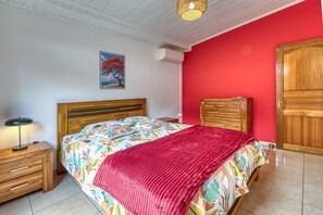 Une chambre à coucher avec un lit en bois, une table de chevet avec une lampe, un mur rouge et une armoire en bois.