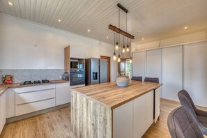 A modern kitchen with a central island, stainless steel appliances, and pendant lighting. - Villa Galéa - Climatisée, vue mer, piscine (Etang-Salé les Hauts)