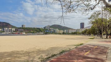 Een strand met een rode looppad, gebouwen op de achtergrond en een heldere lucht.