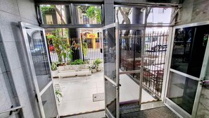 A hotel entrance with a glass door, a bench outside, and potted plants. - Farani (Rio de Janeiro)