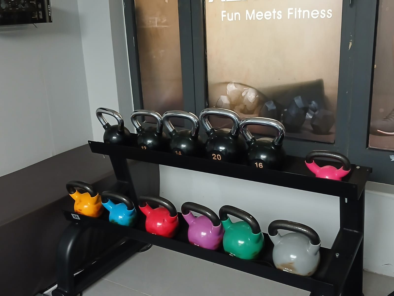 Een halterbank met kettlebells in verschillende gewichten en kleuren.