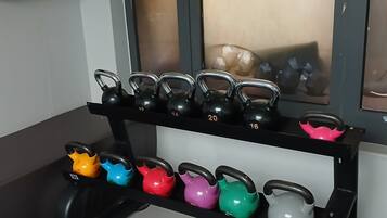 Een halterbank met kettlebells in verschillende gewichten en kleuren.