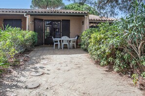 A patio area with a table and chairs, surrounded by greenery and a tiled roof. - L'Écrin de Saint-Cyprien - 2km du Port (Saint-Cyprien)