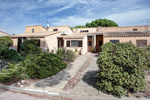 Ein traditionelles Gebäude im mediterranen Stil mit Ziegeldach, Steinweg und üppiger Bepflanzung.