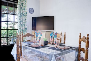 A dining table set with glassware and napkins, a clock on the wall, and a window with curtains. - L'Écrin de Saint-Cyprien - 2km du Port (Saint-Cyprien)