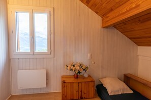 Ett rum med träväggar, ett fönster, ett element, ett träskåp, en säng och en lampa.