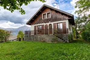 Eine Chalet mit steinernem Fundament, Holzbauweise und einem Balkon mit Metallgeländer.