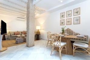 A modern living space with a sofa, dining table, chairs, and a TV. - Genteel Home Patio del Arenal 001 (Seville)